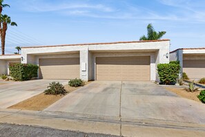 A two-story house with a garage, a driveway, and landscaping. - Dog-Friendly Updated Condo Next to Golf Courses w/WiFi, AC, W/D, Shared Pool (Palm Desert)