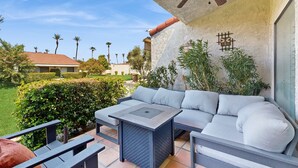 An outdoor patio with a gray sofa, a small table, and a ceiling fan. - Dog-Friendly Updated Condo Next to Golf Courses w/WiFi, AC, W/D, Shared Pool (Palm Desert)
