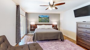 A bedroom with a bed, nightstands, a dresser, a ceiling fan, and a painting on the wall. - Welcoming home with private outdoor pool, pool table, patio, grill & central AC (Phoenix)