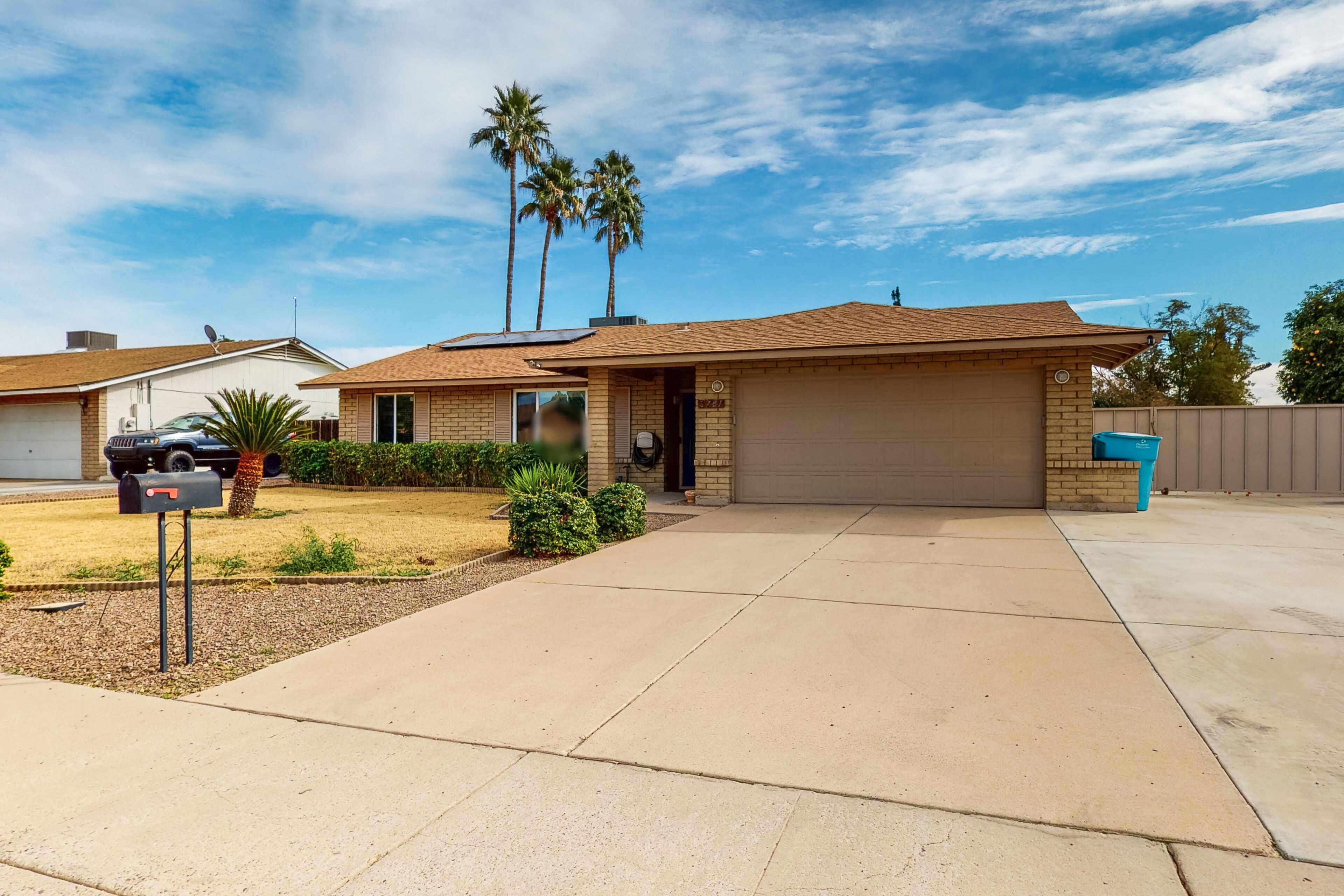 A single-story house with a garage, a driveway, and a mailbox.