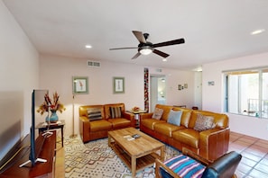 A living room with a sofa, coffee table, and a ceiling fan. - Corner condo in Tucson foothills w/ a community pool & two private patios (Tucson)