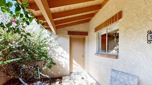 Un patio exterior con techo de madera, una puerta y una ventana con un adorno colgante.