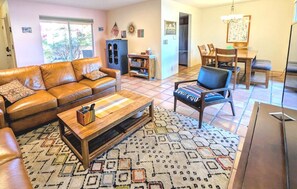 A living room with a leather sofa, a coffee table, and a patterned rug. - Corner condo in Tucson foothills w/ a community pool & two private patios (Tucson)