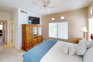 A bedroom with a bed, a wooden dresser, a television, and a ceiling fan. - Spacious, dog-friendly condo with pool & hot tub (Oro Valley)