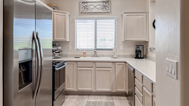 Una cocina moderna con electrodomésticos de acero inoxidable, una ventana con persianas y una cafetera.