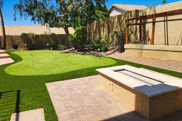 A backyard with a well-maintained lawn, a stone patio, and a wooden pergola. - Tropical retreat with pool, grill, central air-conditioning, & washer/dryer (Phoenix)