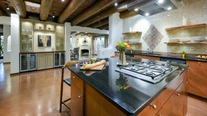 A modern kitchen with a central island, stainless steel appliances, and a rustic wooden ceiling. - Catalina Foothills oasis on 2.1 acres with private pool & putting green (Tucson)