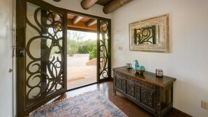 An interior with a wooden ceiling, a patterned rug, a decorative cabinet, and a framed mirror. - Catalina Foothills oasis on 2.1 acres with private pool & putting green (Tucson)