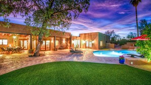 A modern outdoor patio area with a pool, seating, and a dining setup. - Catalina Foothills oasis on 2.1 acres with private pool & putting green (Tucson)