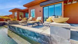 A modern house with a swimming pool, outdoor seating, and large windows. - Lakeside luxury home w/ private pool & spa, fireplace & outdoor kitchen-dog ok (La Quinta)