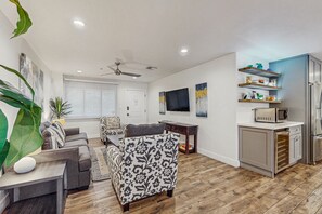 A modern living room with a sofa, a patterned armchair, a dining table, and a kitchen area with a refrigerator and microwave. - Amazing Old Town location above Grimaldi (Scottsdale)