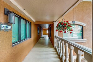 Ein Flur mit Hinweisschild, einer blumengeschmückten Pflanze und einem Fenster mit Blick.