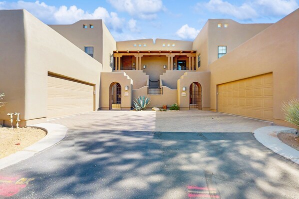 Un bâtiment moderne doté d’une entrée centrale, de deux garages et d’une allée aménagée.