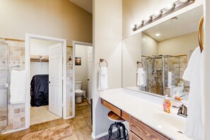 A bathroom with a large mirror, a shower, and a toilet.