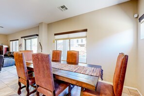 A dining area with a wooden table and leather chairs, a rug, and a window with blinds.
