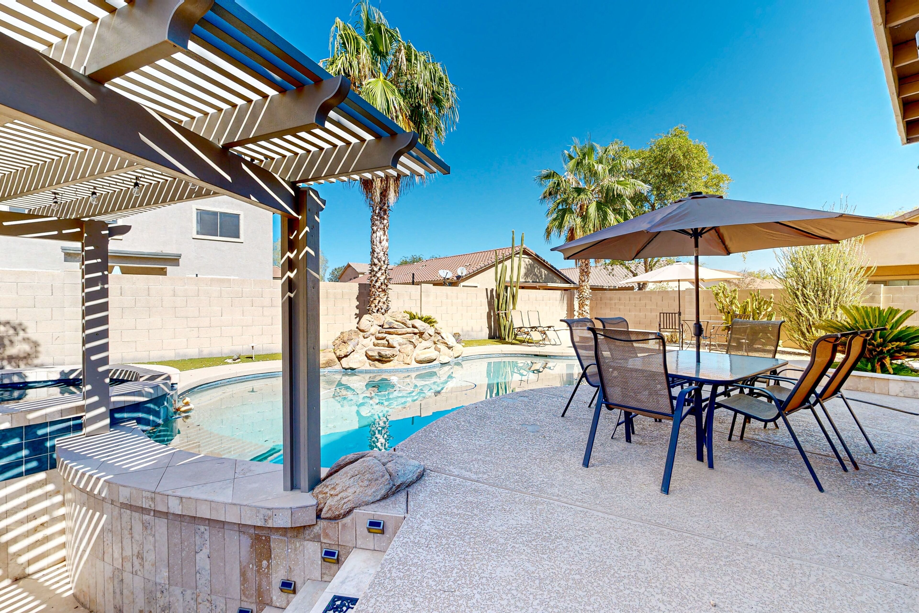 A swimming pool with a pergola and patio furniture.