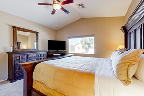 A bedroom with a bed, a dresser, a television, and a ceiling fan.
