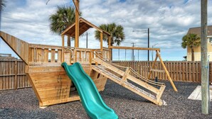 A wooden play structure with a slide, stairs, and a small house-like addition. - Ocean's 96 by Avantstay Heated Pool + Foosball Table + Media Room + Walk to North Padre Beach (Corpus Christi)