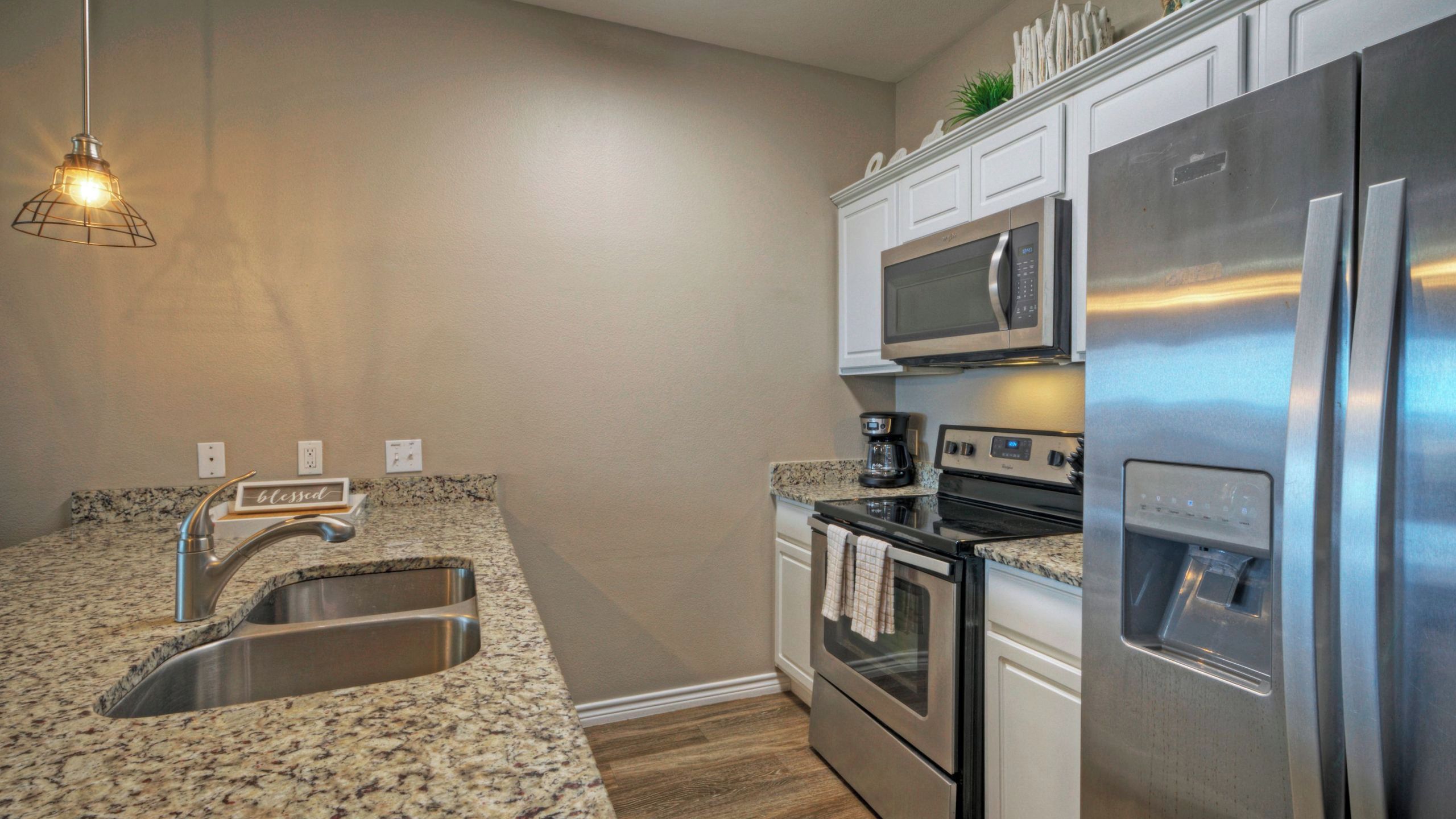 A kitchen with granite countertops, stainless steel appliances, a built-in microwave, and a coffee maker.