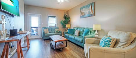 A living room with a wooden coffee table, two sofas, a TV, and a ceiling fan.