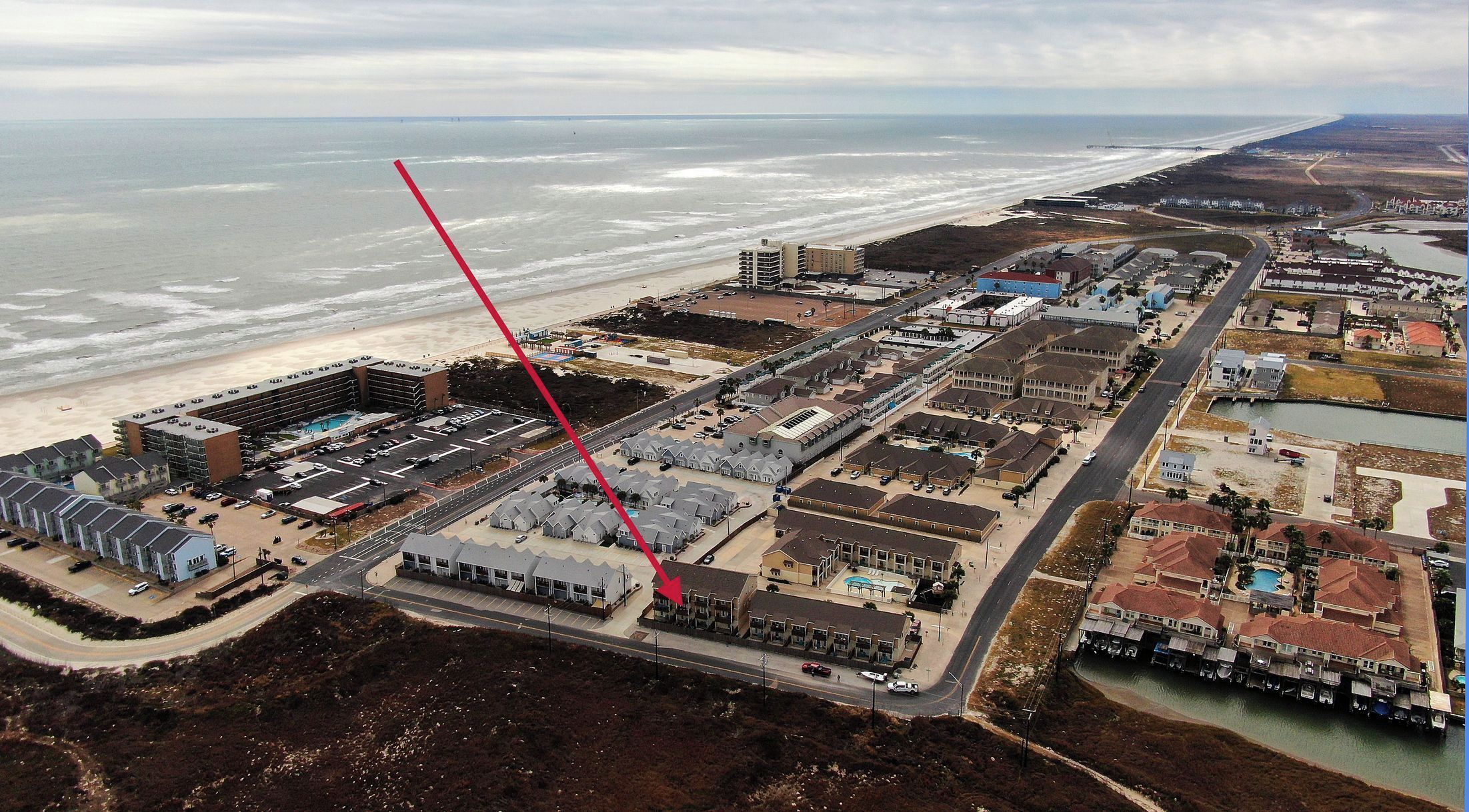 Vista aérea de una zona costera con un gran complejo hotelero, una playa y un puerto deportivo.