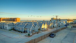 A row of beachside cabins with a parking lot and a view of the ocean. - Ocean's 96 by Avantstay Heated Pool + Foosball Table + Media Room + Walk to North Padre Beach (Corpus Christi)