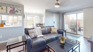 A modern living room with a blue leather sofa, a glass coffee table, and artwork on the wall. - Golf-course-front condo near Old Town with two patios, WiFi, pool & hot tub (Scottsdale)
