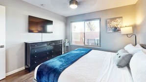 A bedroom with a bed, dresser, window, and artwork. - Golf-course-front condo near Old Town with two patios, WiFi, pool & hot tub (Scottsdale)