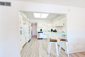 A modern kitchen with white cabinetry, a central island with stools, and a dishwasher. - Dog-friendly house with retro feel, pool, fireplace & patio - snowbirds welcome (Scottsdale)