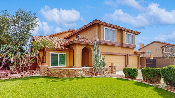 A two-story house with a tiled roof, a stone foundation, and a well-maintained lawn. - Scottsdale Style Meets Family-Friendly Fun! Spacious home with a yard and pool. (Scottsdale)
