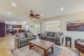 A spacious living area with two sofas, a coffee table, and a ceiling fan. - Scottsdale Style Meets Family-Friendly Fun! Spacious home with a yard and pool. (Scottsdale)