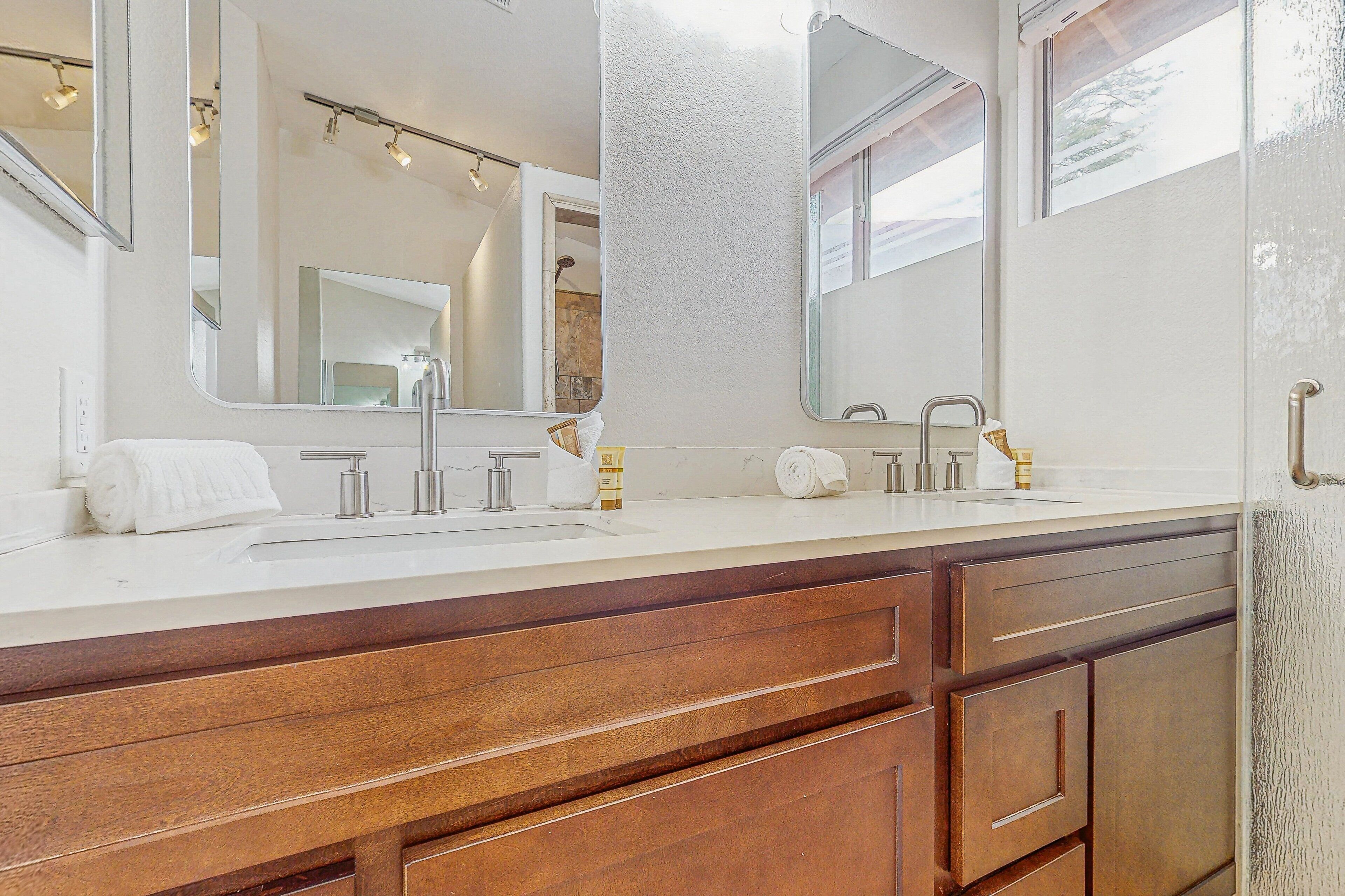 Une salle de bain avec un double lavabo, un meuble-lavabo en bois et de grands miroirs.