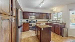 A kitchen with wooden cabinets, stainless steel appliances, granite countertops, and a large window. - Scottsdale Style Meets Family-Friendly Fun! Spacious home with a yard and pool. (Scottsdale)