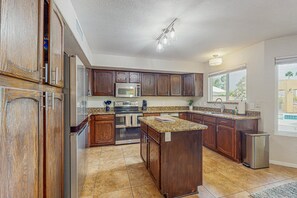 A kitchen with wooden cabinets, stainless steel appliances, granite countertops, and a large window. - Scottsdale Style Meets Family-Friendly Fun! Spacious home with a yard and pool. (Scottsdale)
