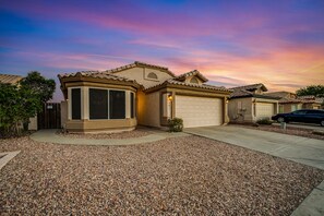 A residential house with a garage, a driveway, and a gravel front yard. - Sunny & stylish home with private pool, central AC, W/D & firepit (Glendale)
