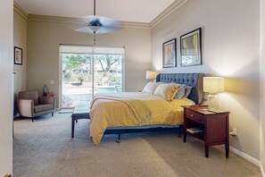 A bedroom with a bed, a nightstand, a chair, and a ceiling fan. - Dog-Friendly Golfer's Haven w/Private Pool & Spa - On 6th Hole of Dunes Course (La Quinta)