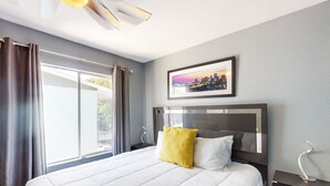 Ein Hotelzimmer mit einem großen Bett, einem Stadtbild an der Wand und Blick ins Freie durch das Fenster.