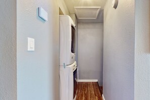 A narrow hallway with a white appliance, possibly a washer and dryer, against a light-colored wall. - Snowbird-Friendly Condo with Patio Access, Central AC, Free WiFi - Dogs Welcome (Glendale)