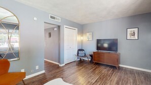 Ein modernes Wohnzimmer mit Holzböden, einem Fernseher, einer Holzschrank und einem Sessel.