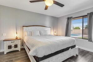 A bedroom with a bed, nightstand, lamp, ceiling fan, and a window with curtains. - Dog-friendly home with private pool, great backyard, and free WiFi (Mesa)
