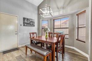 A dining area with a wooden table, chairs, a bench, a chandelier, and windows with blinds. - Dog-friendly home with private pool, great backyard, and free WiFi (Mesa)