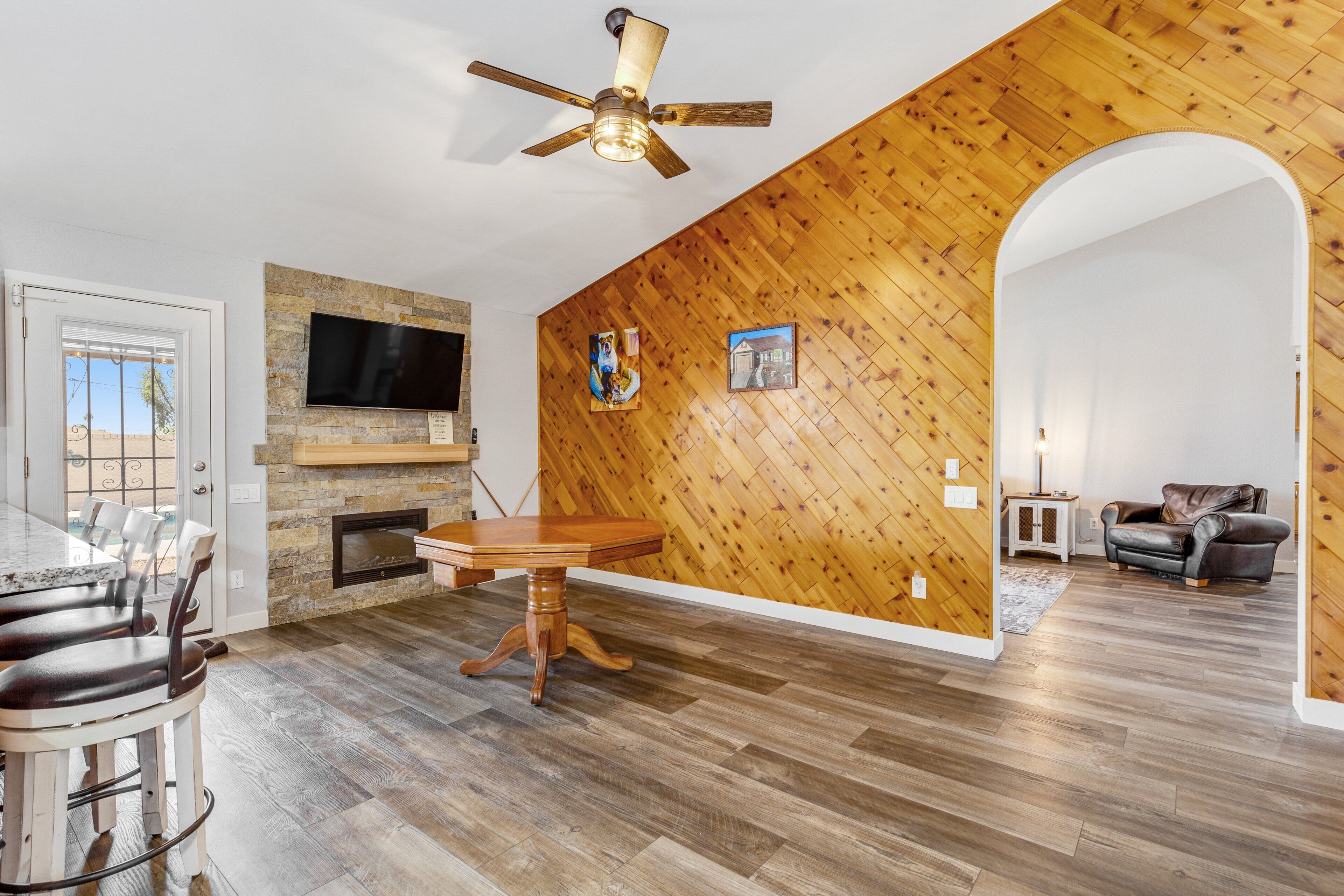 A spacious living area with a wooden wall, a fireplace, a dining table, and a leather sofa.