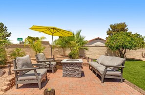 An outdoor patio area with stone seating, a fire pit, and a yellow umbrella. - Dog-friendly home with private pool, great backyard, and free WiFi (Mesa)