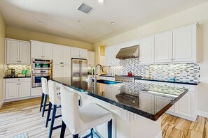 A modern kitchen with white cabinets, stainless steel appliances, and a black granite countertop. - Trilogy Polo Club home w/private jacuzzi, Peloton, shared pool & tennis courts (Indio)