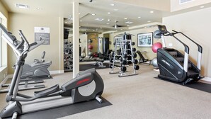 Un gimnasio con cintas de correr, elípticas y equipo de levantamiento de pesas.