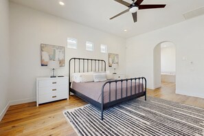 A bedroom with a bed, bedside tables, a ceiling fan, and a large window. - Quiet Dog-Friendly Desert Getaway w/ Private Pool, Spa & Mountain Views (Palm Desert)