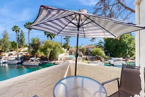 Eine Terrasse mit Tisch und Stühlen mit Blick auf eine Marina, wo Boote und ein Pool liegen.