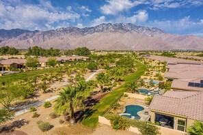 A residential area with houses, a swimming pool, and mountains in the background. - Mountain view home, private pool & spa - shared pools, tennis, fitness center (Cathedral City)