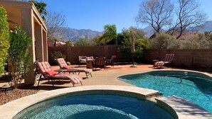 Ein Garten mit Swimmingpool, Liegestühlen und einer Terrassenfläche.