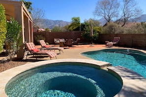 A backyard with a swimming pool, lounge chairs, and a patio area. - Contemporary & comfortable home with a pool, WiFi, washer/dryer & central air-conditioning (Oro Valley)